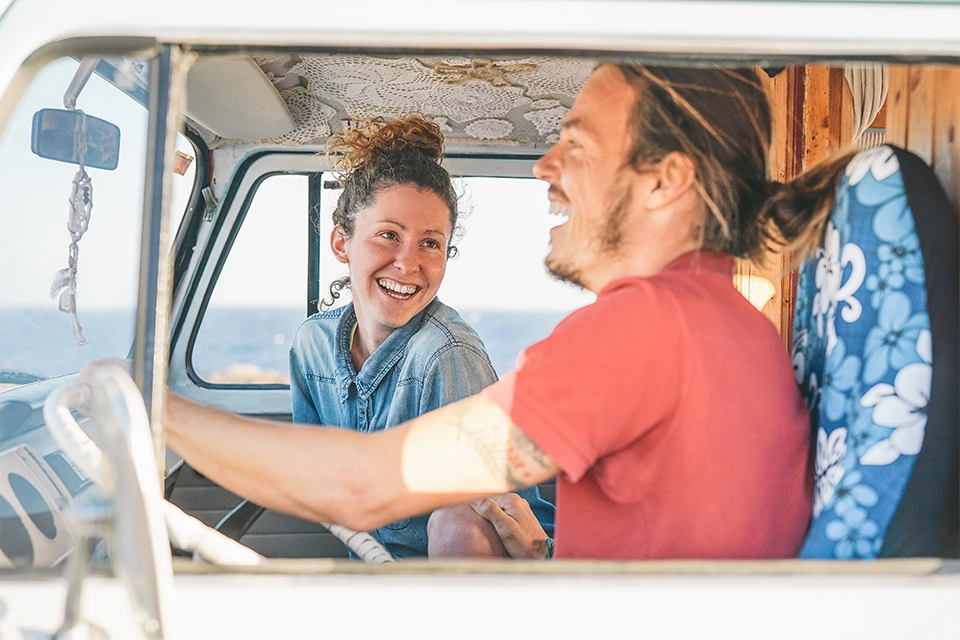 Two travel content creators in a van laughing