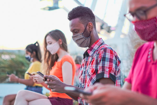 Four people in facemasks looking at their smartphones