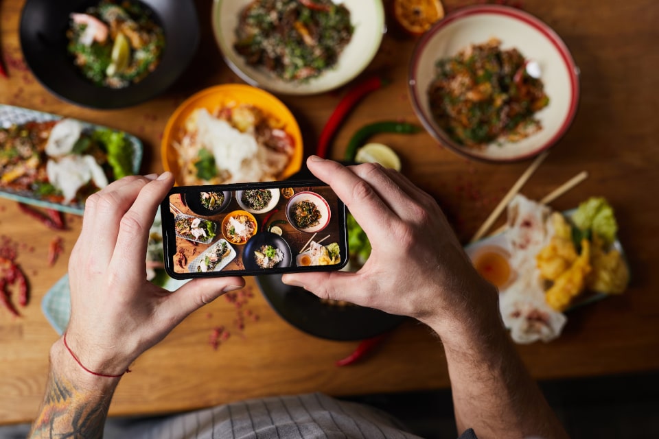 Someone taking a picture on their smartphone of dishes of food
