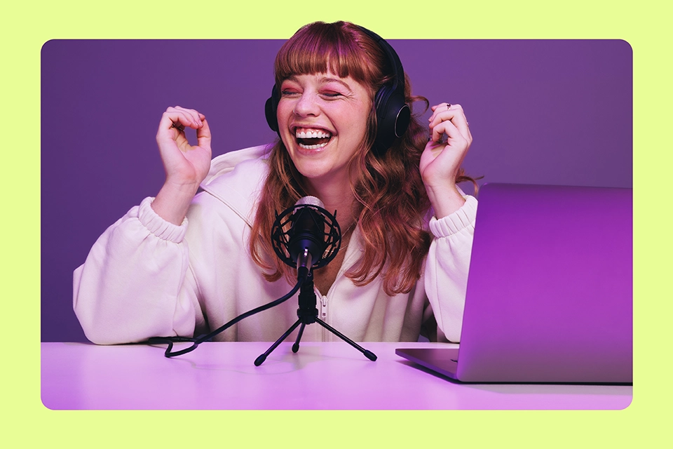 Smiling influencer with headphones in front of a mic