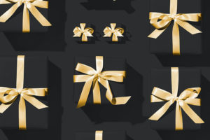 Black presents wrapped with gold ribbon on a black baground