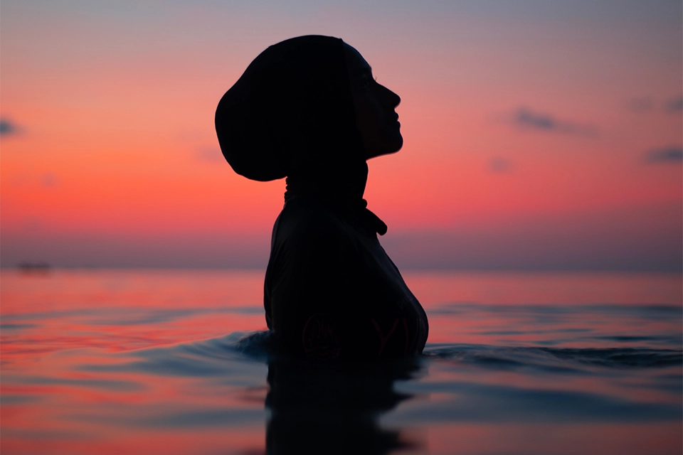 Shadowed profile of a woman in the water at sunset indicating shadow banning