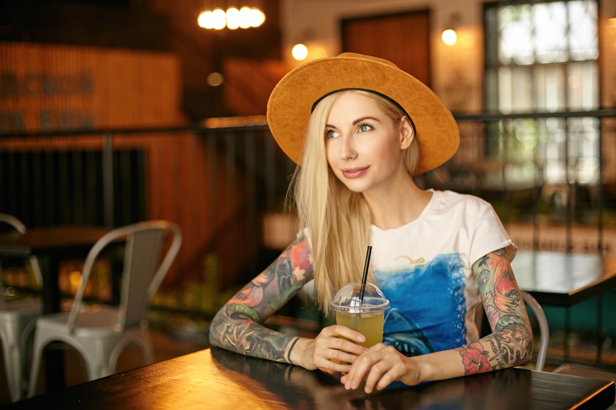 Tattoo influencer with hat and drink