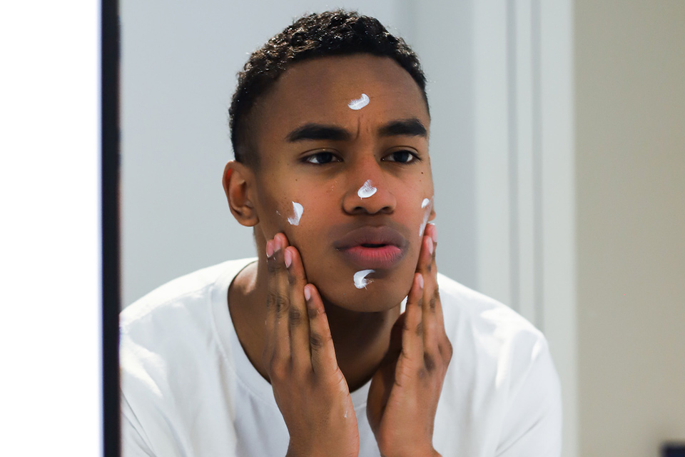 Skincare influencer putting cream on his face