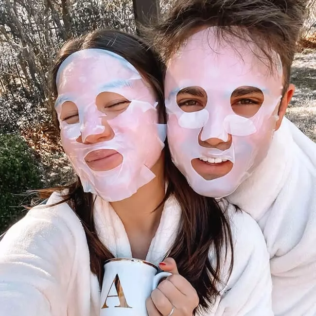 Couple with robes and cosmetic facial masks on