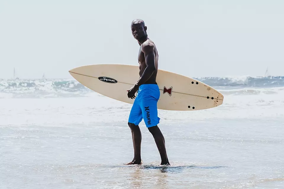Man with branded trunks and surfboard on the beach