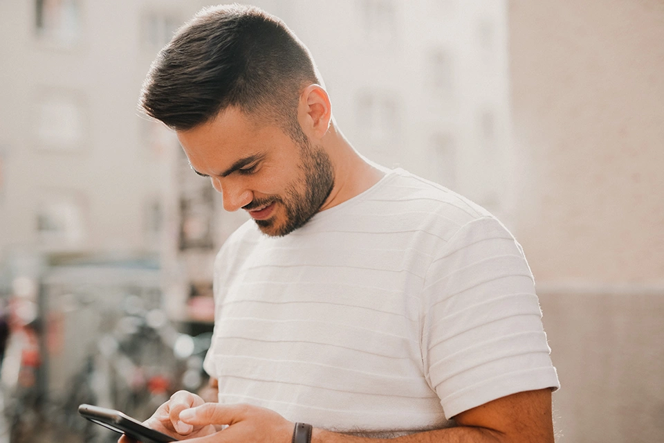 El hombre sonríe en su teléfono después de que una marca se dirigió a Instagram con un correo electrónico de alcance de personas influyentes