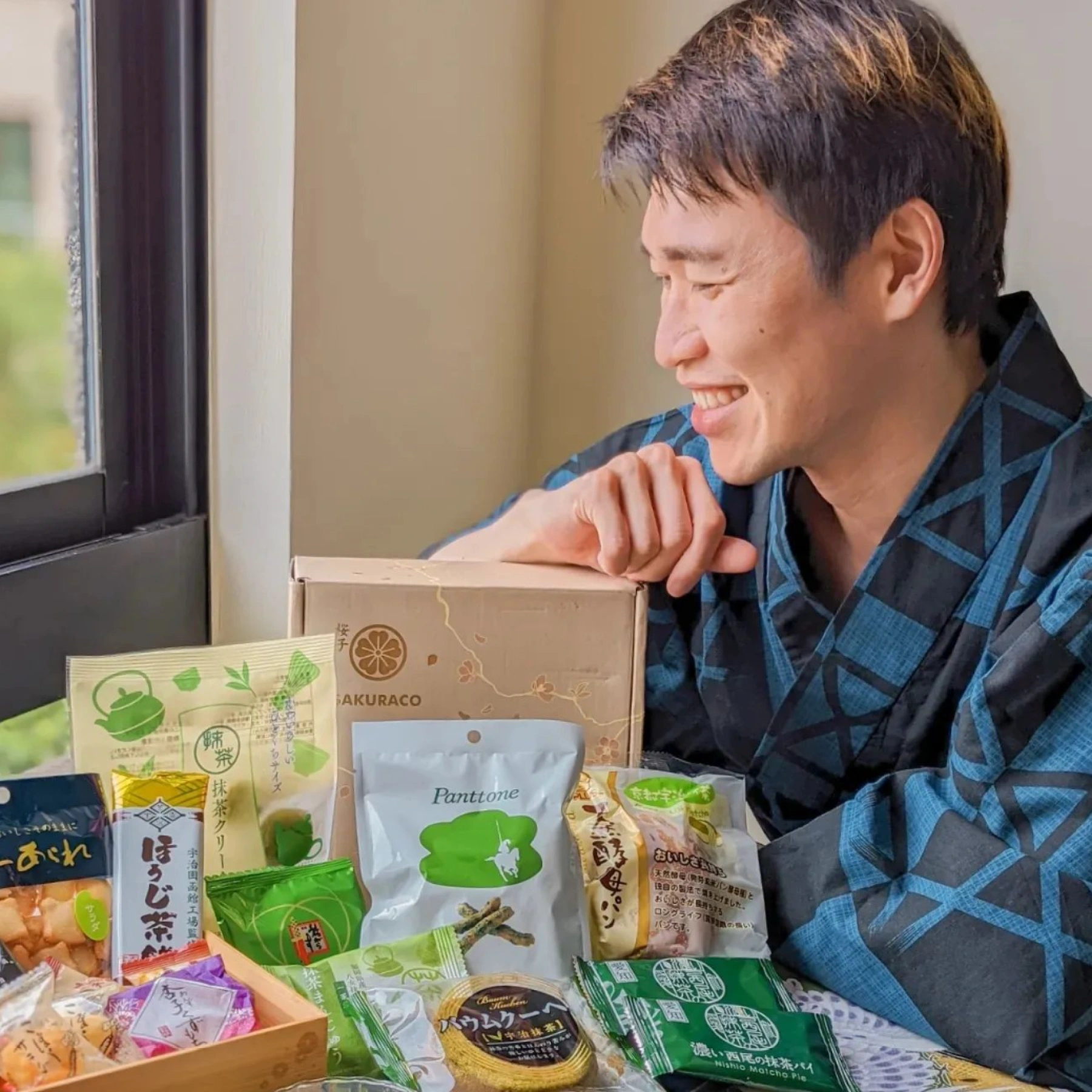 Smiling man behind many Sakuraco snacks