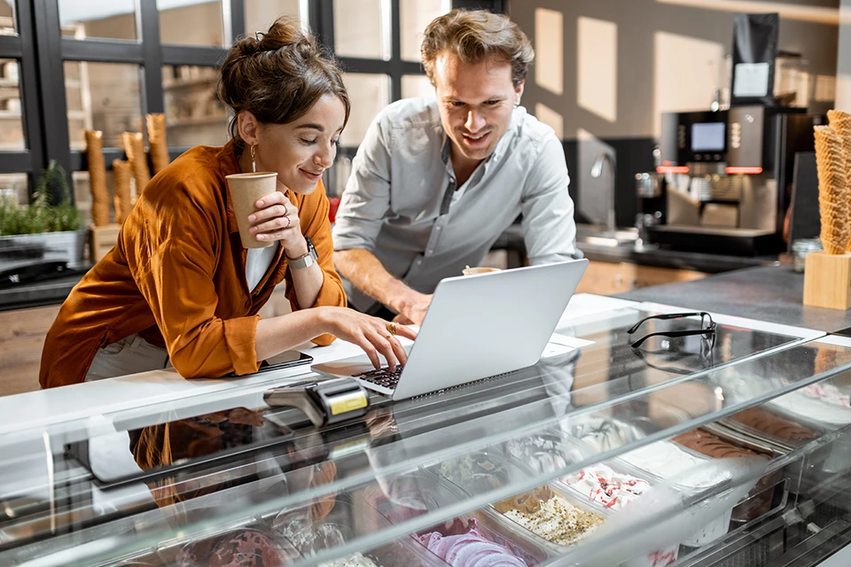Dos dueños de cafeterías discuten el marketing de influencers de pequeñas empresas a través de una computadora portátil