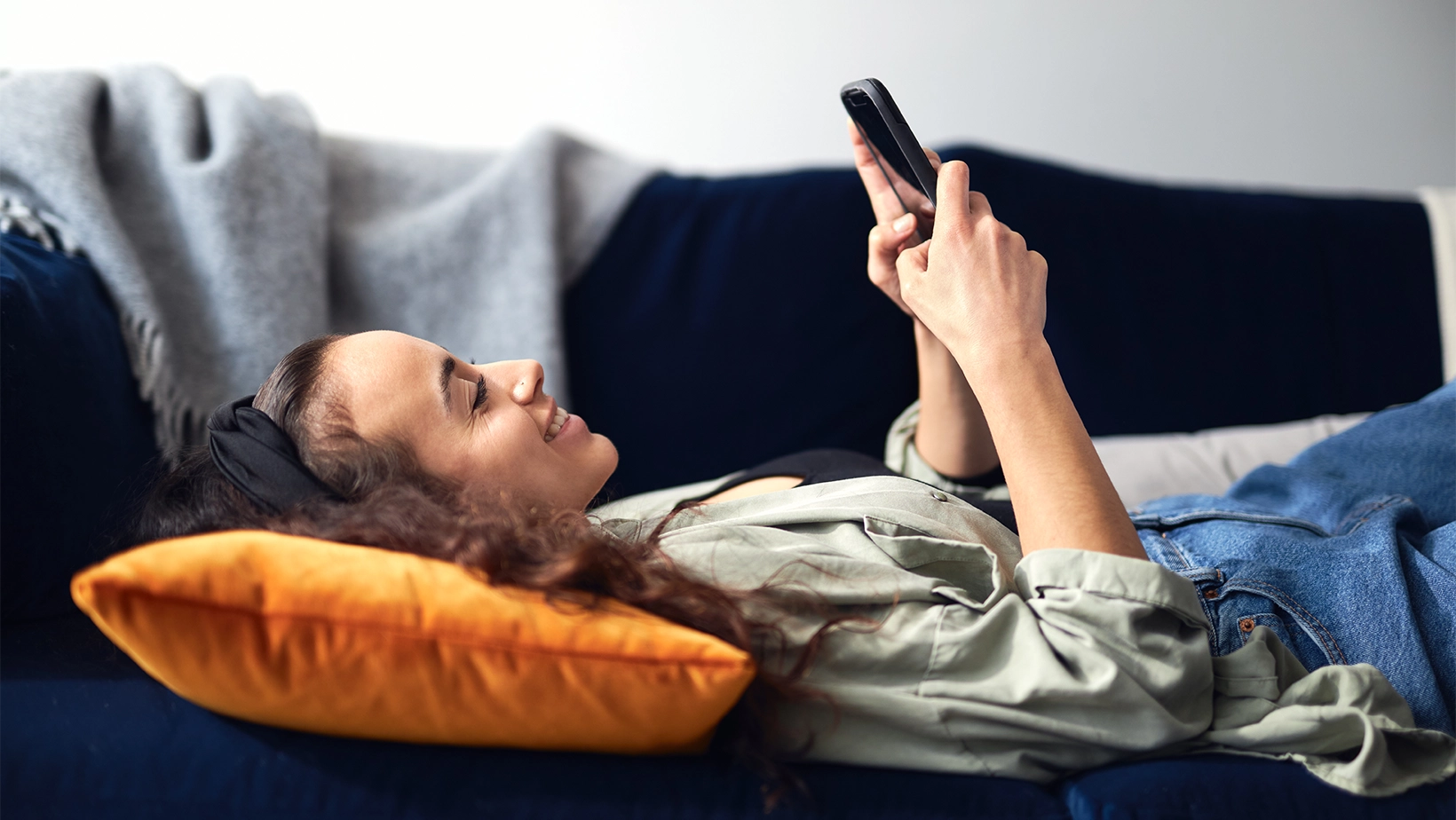 Woman looking at her phone while lying on a couch