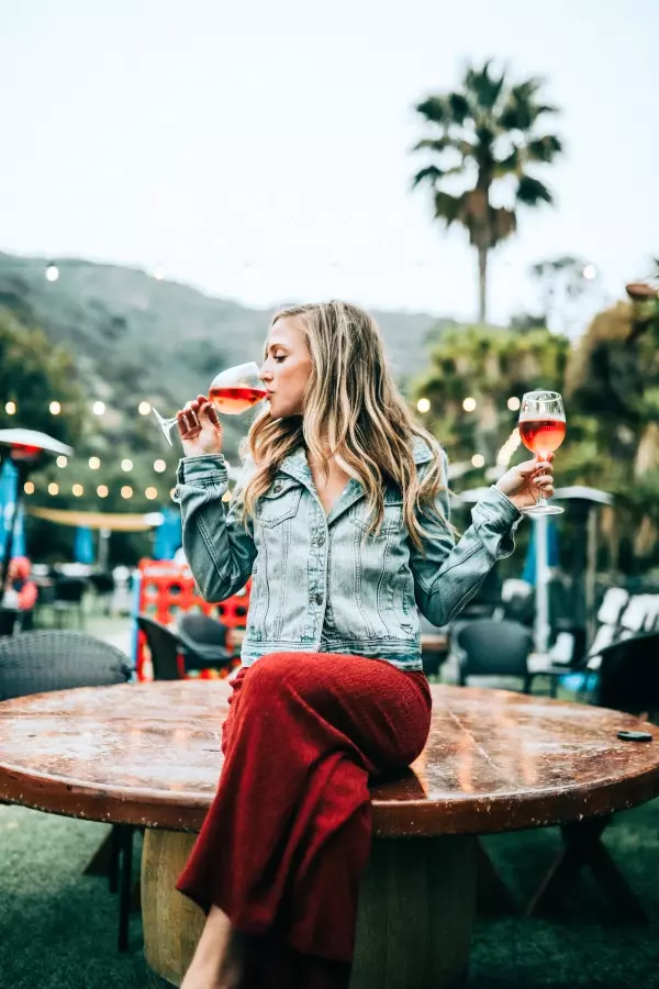 alcohol influencer drinking one glass of rose while holding another 