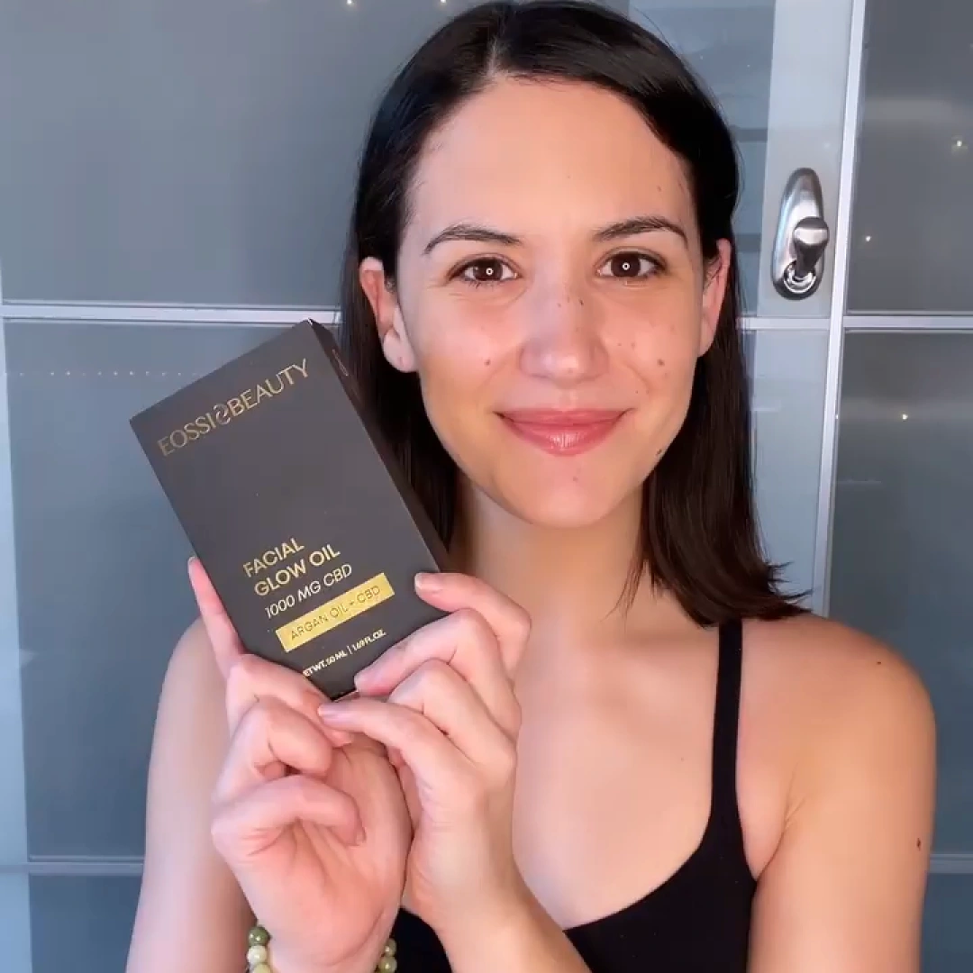 Woman holding up an Eossi Beauty Facial Glow Oil box