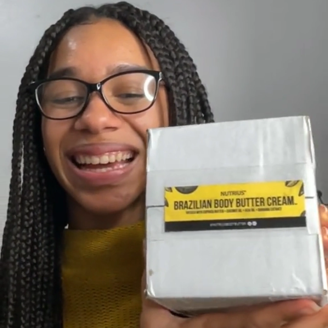 Woman holding up a Nutrius Brazilian body butter cream box