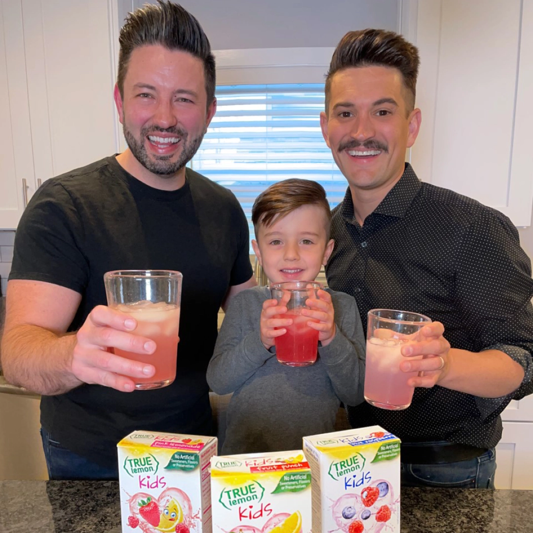 Two men and a boy smiling and holding True Citrus drinks