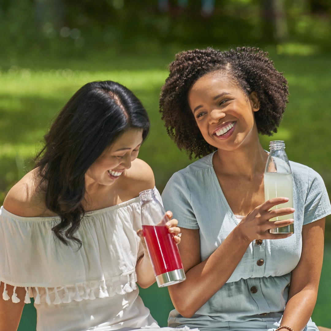 Two women laughing holding True Citrus drinks