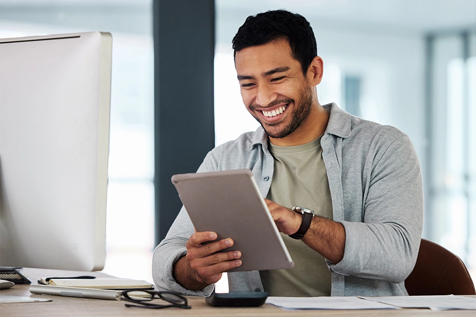 Man happily looking at a tablet while researching content management software