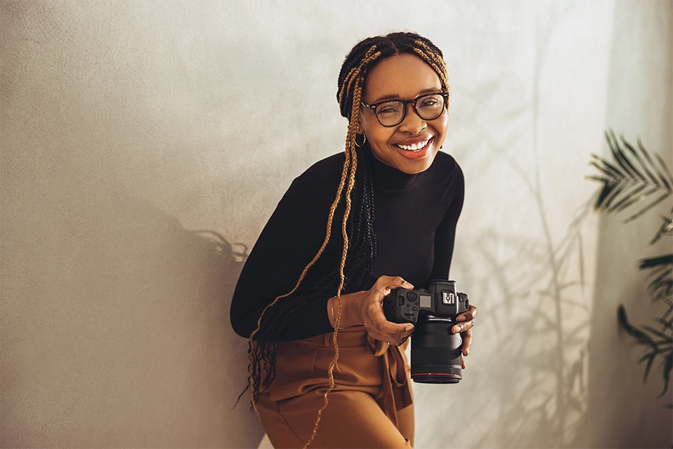 Woman smiling and holding a camera to take pictures for a business Instagram profile