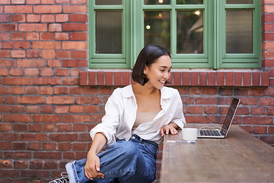 Woman smiling at a laptop reading about influencer tax obligations