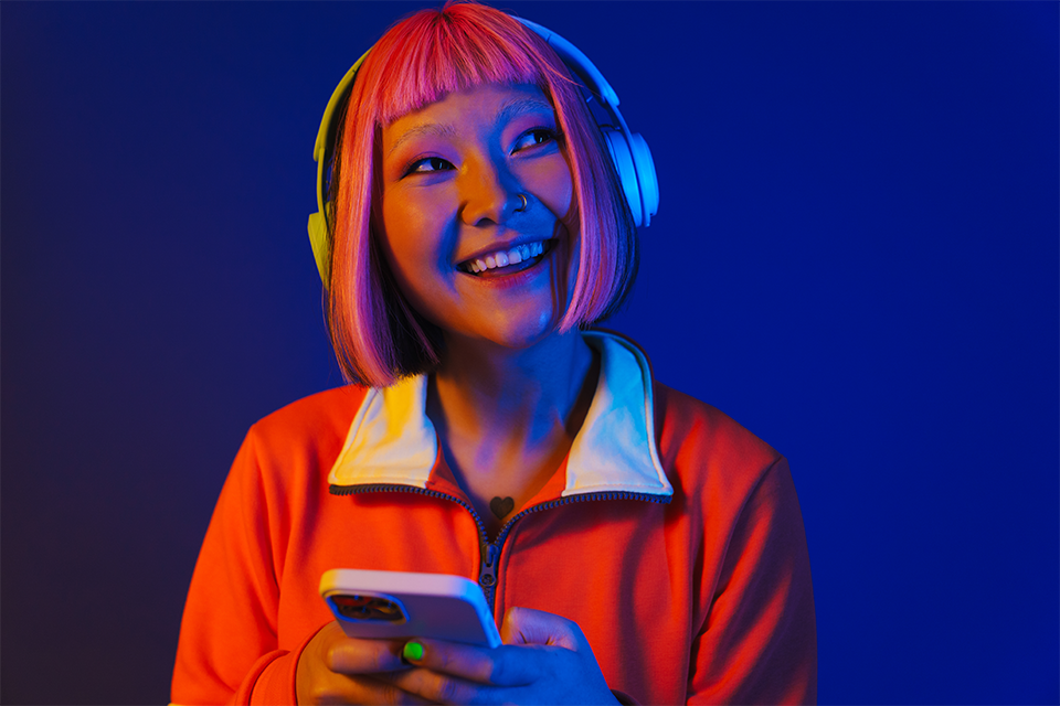 Woman with headphones holding a smartphone happy because of app marketing best practices