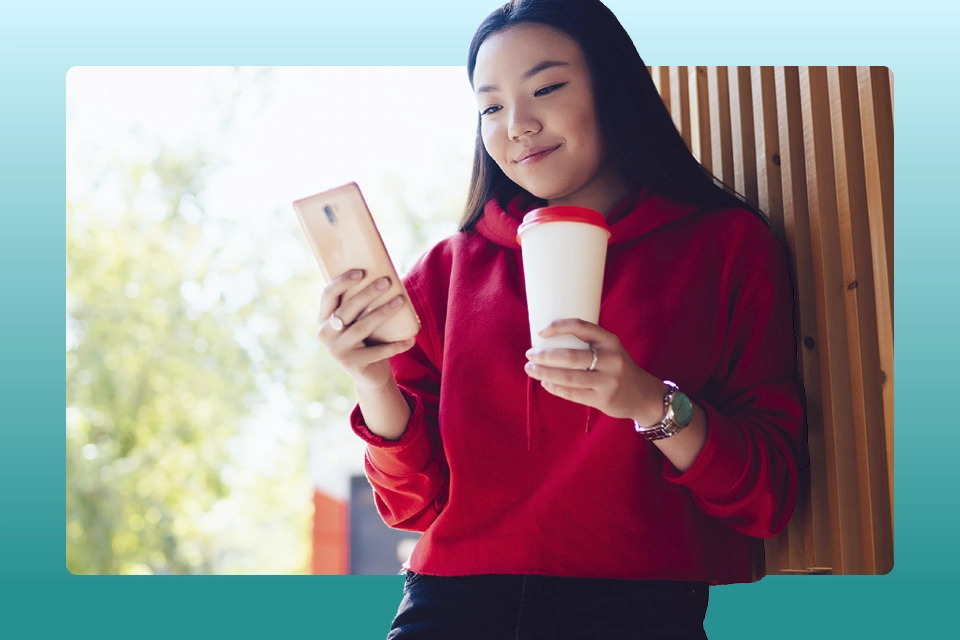 influencer holding coffee and looking at a smartphone in an example of using influencer marketing to grow your business