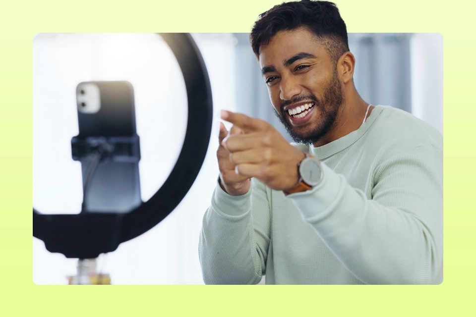 Happy influencer pointing at a camera with a ring light as a an example of customer advocacy in email marketing