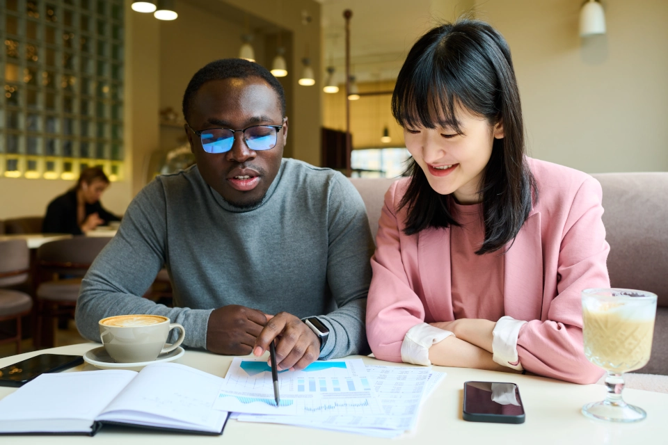 Two people demonstrating how to create a customer loyalty program by pouring over data on a table