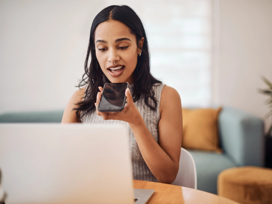 woman speaking into a phone looking at a laptop symbolizing easier communication with a creator marketplace